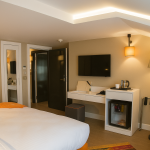 Sparkle Hotel Family Suite içinde geniş yatak, çalışma alanı, TV ünitesi ve mini buzdolabı bulunan modern aile odası