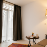 Sparkle Hotel Junior Suit oturma odasında gün ışığı alan geniş pencere, modern koltuk takımı ve sıcak aydınlatmalı rahat yaşam alanı.